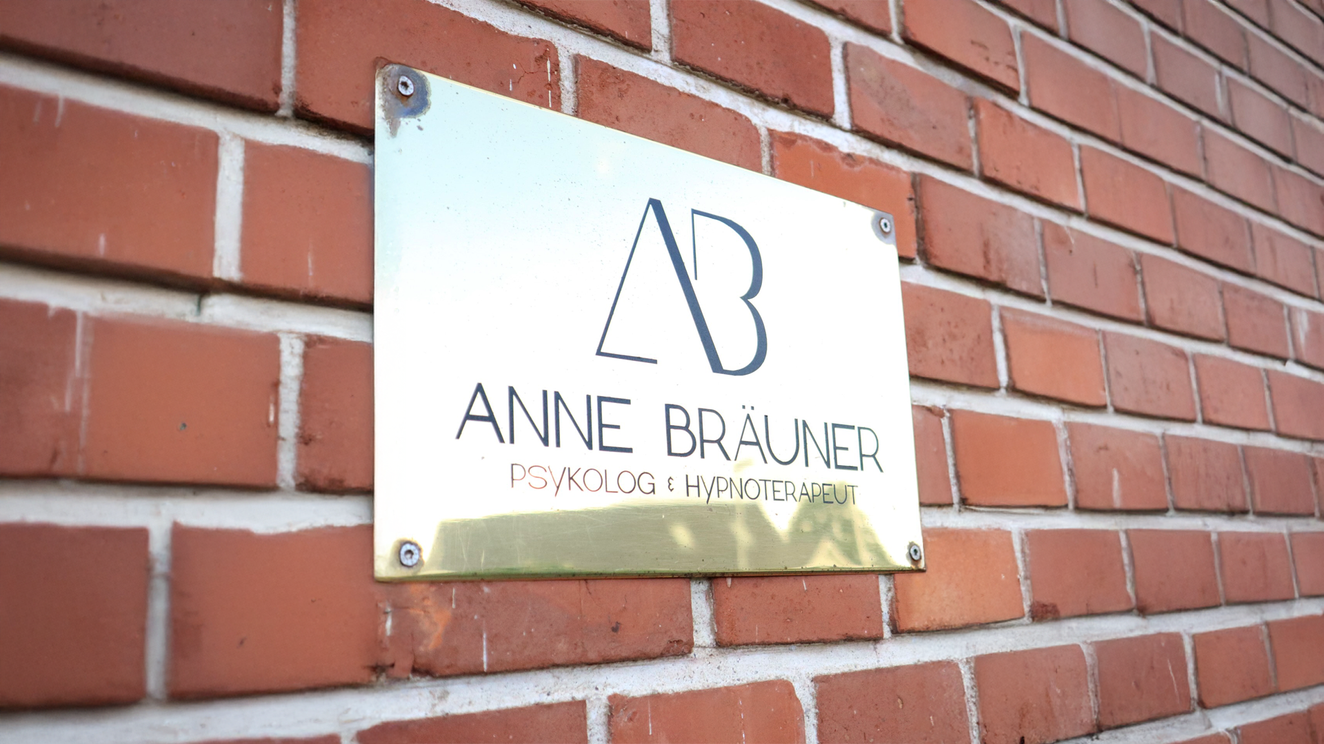 Skilt på mur med Anne Bräuner, psykolog og hypnoterapeut.